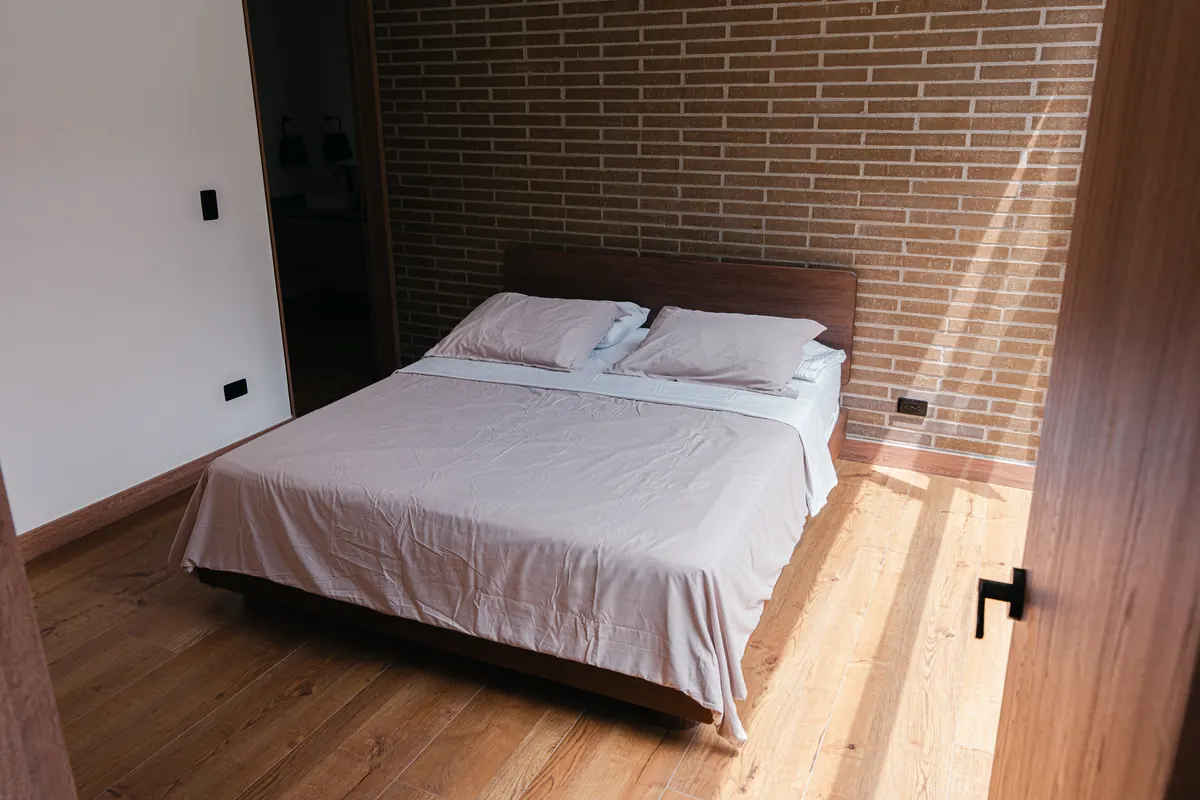 Habitación con cama Queen y muro en ladrillo