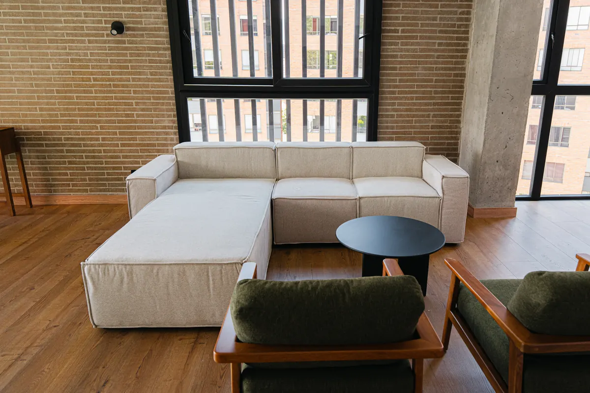Sala del penthouse con ventanales de doble altura y muro en ladrillo