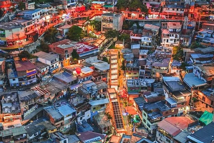 Vista aérea de la Comuna 13 al atardecer, con las escaleras eléctricas iluminadas
